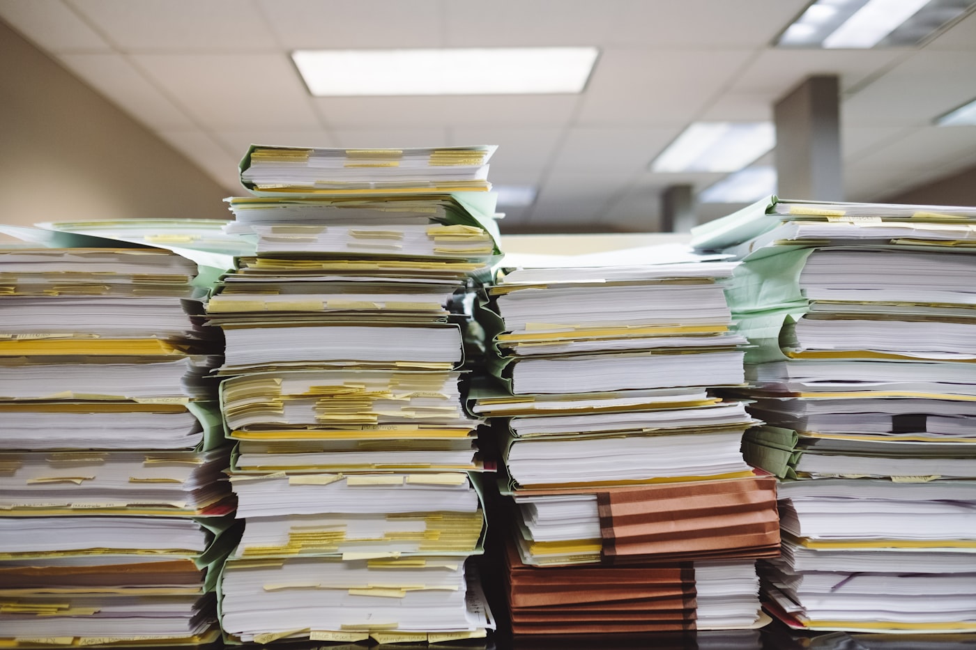 Stacked document folders and paperwork awaiting reconciliation.